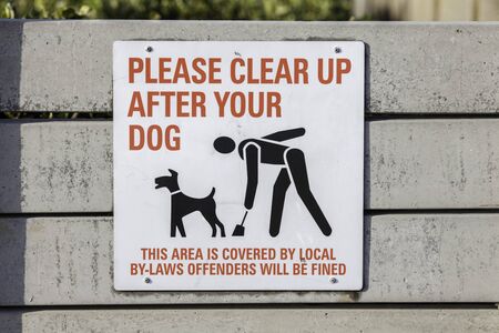 Please clear up after your dog. A written sign with an image of a responsible pet owner cleaning up after their dog.の写真素材