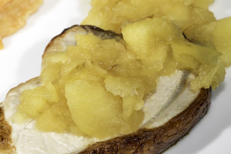 Homemade apple sauce on a pork loin steak. Meal serving on a white plate.の写真素材