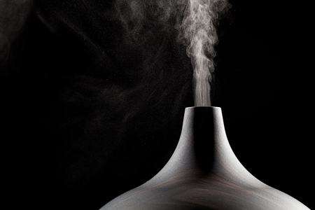 Close up of an ultrasonic aromatherapy oil diffuser in use. Atomized water droplets being dispensed into the air.