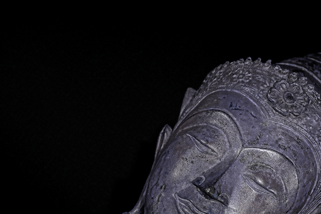 Chill out. Modern spirituality with buddhism. Silver sleeping buddha head at an angle against black background with with copy space. High contrast contemporary image.の写真素材