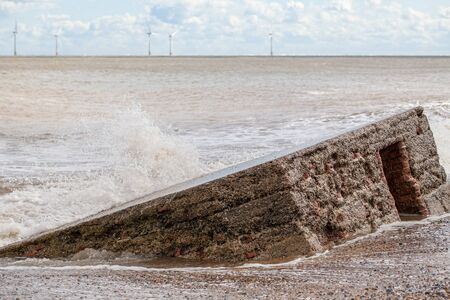 Coastal erosion and rising sea level reclaiming a WW2 anti-invasion beach defence building on the East Coast of England. World War 2 concrete coastal invasion structure. の写真素材
