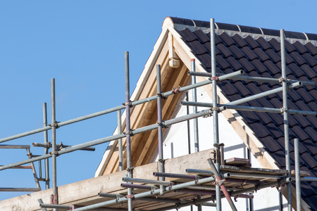 Modern house roof construction with scaffold pole platform. New build domestic building.の写真素材
