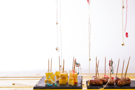 Party food leftovers. Cheese and pineapple and cocktail sausages on sticks. Leftover nibbles with party popper streamers in front of white background with copy space.の写真素材