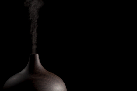 Spa treatment diffuser device. Alternative therapy electronic atomizer in use. Poster image against black background with copy space.の写真素材
