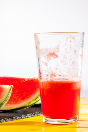 Cooling summer fruit drink. Watermelon smoothie. Thirst quenching iced crush with fresh watermelon slices. White background with copy space.の写真素材