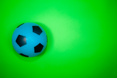 Soccer ball. Blue and black football on plain green background with copy space.の写真素材