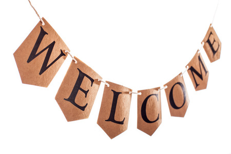 Welcome banner. Welcome text hanging on bunting in selective focus against white background. The...