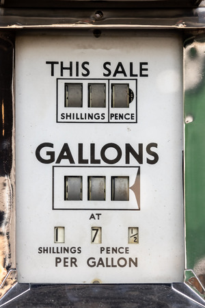 The price of petrol. Vintage car fuel pump meter with gallons priced in shillings and pence. Retro gasoline station. Antique gas dispenser showing inflation in the crude oil and petroleum industry.の写真素材