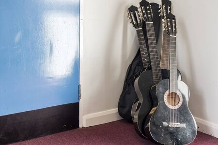 Group of budget classical guitars standing in corner of school music room. Arts department musical...