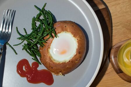 Egg in a bagel hole with samphire. Simple healthy breakfast meal. Close-up flat-lay image of brunch with tomato ketchup.の写真素材