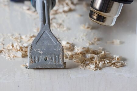 Scraping paint off wood with a hot air gun and tungsten carbide scraper blade. DIY decorating and furniture restoration close-up image of paint removal.の写真素材