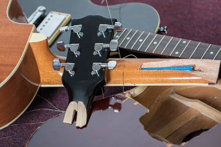 Smashed guitars. Pile of broken electric and acoustic guitar bits. Close-up of damaged musical instruments including headstock, neck and body of various guitars. Frustrated guitarist.の写真素材