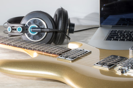 Music production. Writing music with an electric guitar, laptop computer and headphones. Flat lay image of modern music composition on a home studio desk. Guitarist musician desktop recording set up.の写真素材