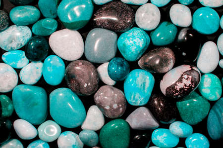 Beach pebbles. Blue, green and turquoise toned stones. Beautiful nature background image on black. Layer of pretty aesthetic rocks. Creativity with natural objects. Creative art design project idea.の写真素材