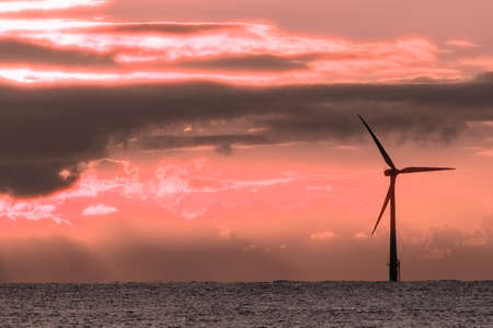 Global warming and climate change. Surreal pink sunset with offshore wind turbine. Modernistic...