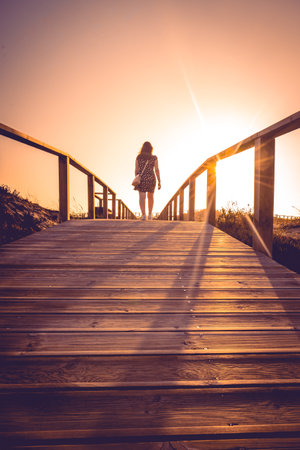 Woman stands on the bridge, watching the sunset.の写真素材