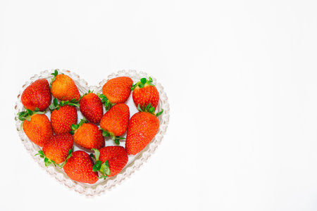 Strawberries in a heart shape on a white background with copy spaceの写真素材