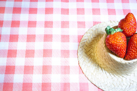 Fresh strawberries decorated on a straw hat. on a red picnic blanket.の写真素材
