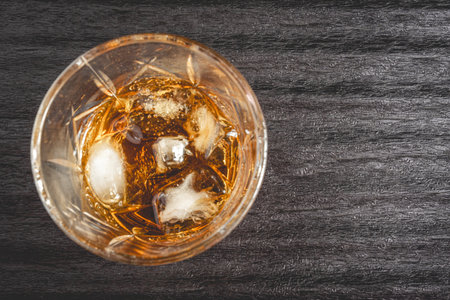 A beautiful glass of whiskey on the rocks, on a black background. Whiskey with ice cubes.の写真素材