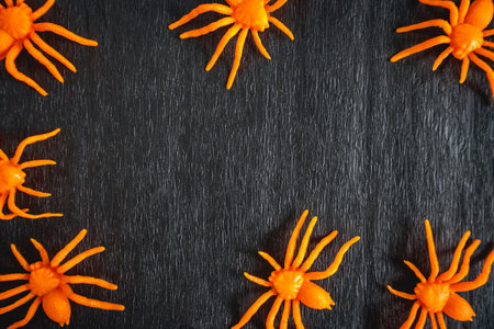 Fake orange spiders on a black background. nice Background for halloween for posters or flyers.の写真素材