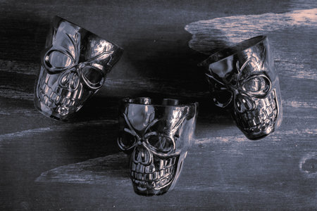 A pair of shot glasses in the shape of a skull, for a Halloween Party. On a wooden background, in...