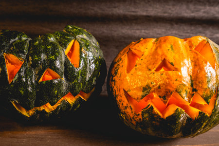 Two small pumpkins carved for Halloween. On a dark background.の写真素材