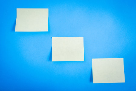 Three empty sticky notes, on a blue background.の写真素材