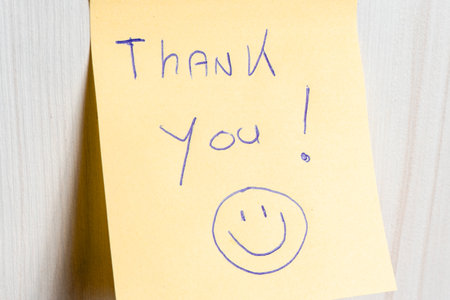 A sticky note hanging on the wall, with the text Thank You on it.