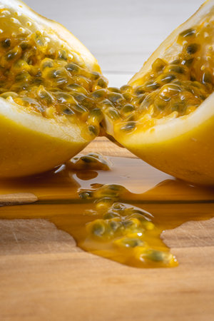Passion fruit cut in half, on a wooden board. with juice coming out.の写真素材