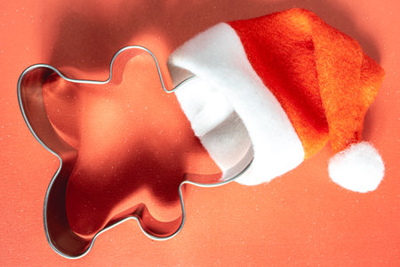 shape for Christmas cookies or ginger bread, with a Santa hat on. On a red background.