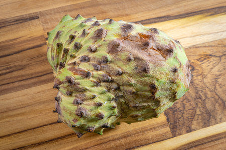 Atemoya, a tropical fuit, laying down on a wooden board, with a white background.の写真素材