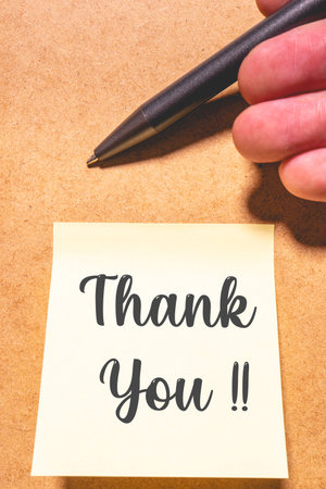 A thank you note with a pen, on a brown background.の写真素材