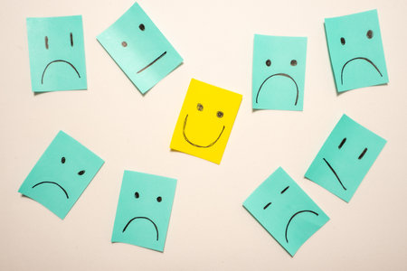 Sticky notes with unhappy smileys and one happy smiley. On a white background.の写真素材