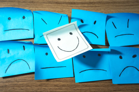 Sticky notes with smileys and one happy smiley. On a wooden background.の写真素材