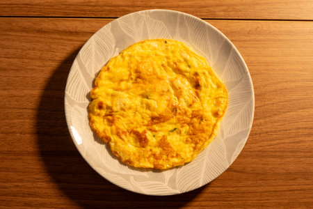 A plate with an egg omelette, on a wooden table.の写真素材