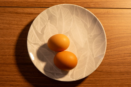 A plate with two eggs on a wooden table.の写真素材