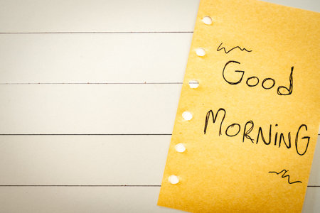 A handwritten note with good morning on it. on a white wooden background.