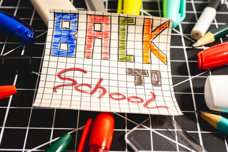 A Note with Back to School on it and different school supplies, on a Black background. Back To School background.