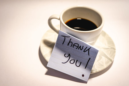 A cup of coffee, and a Thank You note. On a white background.