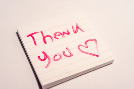 A handwritten note with the text Thank You  on it. On a white background.