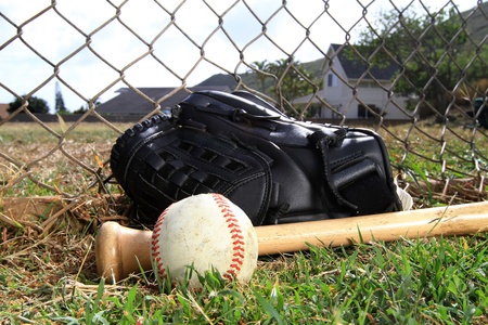 Baseball glove, bat, and ball lay in a fieldの写真素材