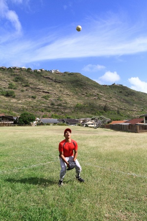 Outfielder watches a fly ball eagerly and prepares to catch itの写真素材