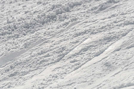 A section of pisted snow, showing ski tracks running across the piste.の写真素材