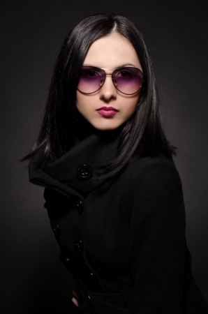 Portrait of a beautiful young woman in sunglasses on black backgroundの写真素材