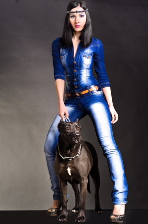 Beautiful woman in denim clothes standing next to a dogの写真素材