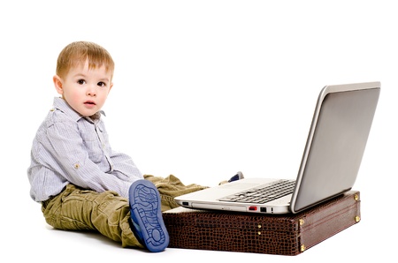 Cute little boy sitting on the floor with a laptop