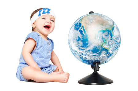 Cute cheerful little girl sitting next to world globe. Elements of this image furnished by NASA.の写真素材