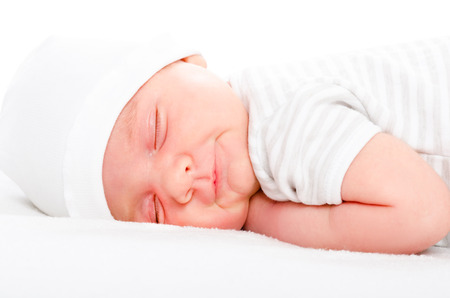Portrait of a smiling newborn baby sleeping on a white backgroundの写真素材