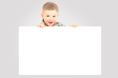 Cheerful boy peeking from behind a bannerの写真素材