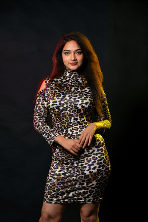 Indoor portrait of a young beautiful fashionable woman wearing stylish Leopard skin garment in black Studio background . Female fashion, beauty and advertisement concept.の写真素材